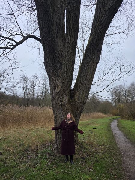 Foto van mij bij een heel grote boom, zonder bladeren, herfstachtig aanblik.